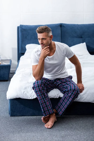 Thoughtful adult man sitting on bed during morning time at home — Stock Photo