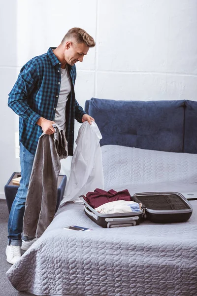 Bello adulto maschio viaggiatore imballaggio bagagli in camera da letto a casa — Foto stock