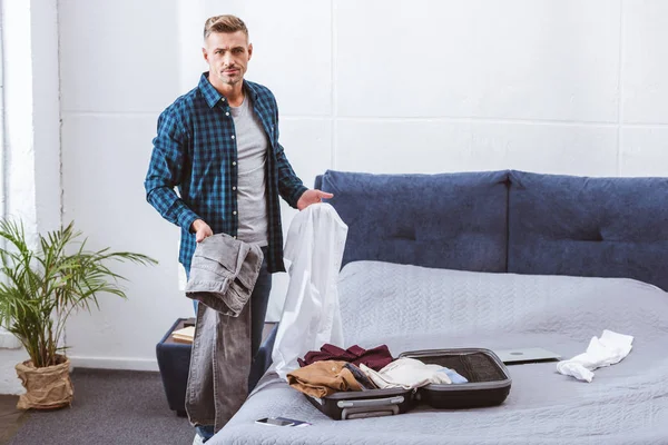 Serious male man packing luggage in bedroom at home — Stock Photo