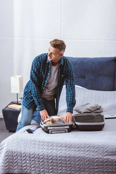 Adulte homme emballage sac à roulettes dans la chambre à coucher à la maison — Photo de stock