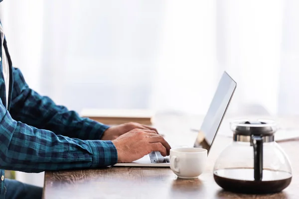 Close-up partial view of man in checkered shirt using laptop at home — Stock Photo