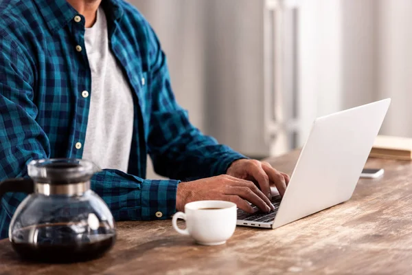 Cropped shot of man in checkered shirt using laptop at home — Stock Photo