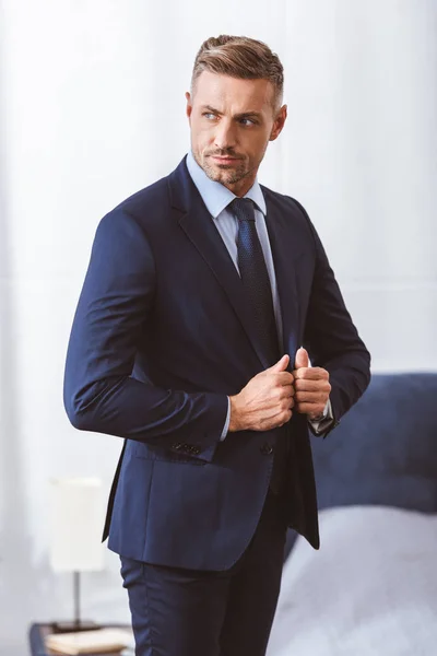 Handsome man wearing suit and looking away at home — Stock Photo