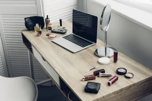 Plan rapproché du lieu de travail avec ordinateur portable et fournitures de maquillage à la maison — Photo de stock