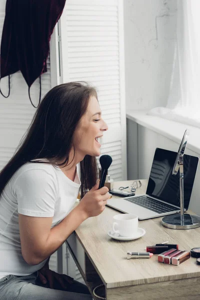 Happy transgender woman doing makeup at workplace at home — Stock Photo