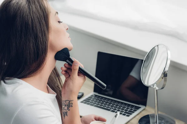 Junge Transgender-Frau schminkt sich am Arbeitsplatz zu Hause mit Pinsel — Stockfoto