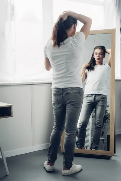 Transgender woman in white t-shirt looking at mirror at home — Stock Photo
