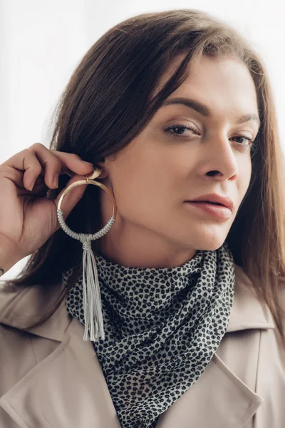 Close-up portrait of young transgender woman putting on earring and looking at camera — Stock Photo