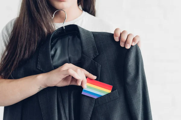 Recortado disparo de mujer transgénero tomando tarjeta con bandera de orgullo de bolsillo del traje de negocios - foto de stock