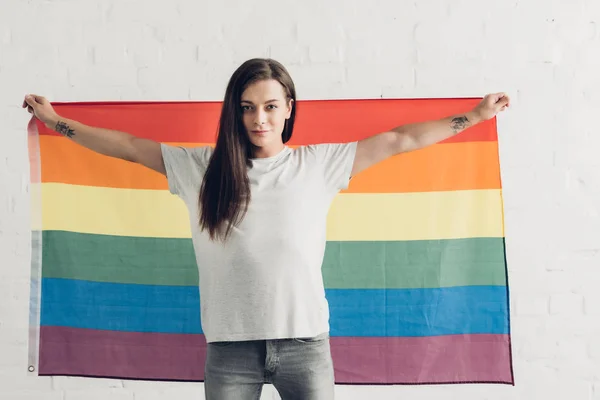 Mulher transexual confiante segurando bandeira orgulho na frente da parede de tijolo branco — Fotografia de Stock