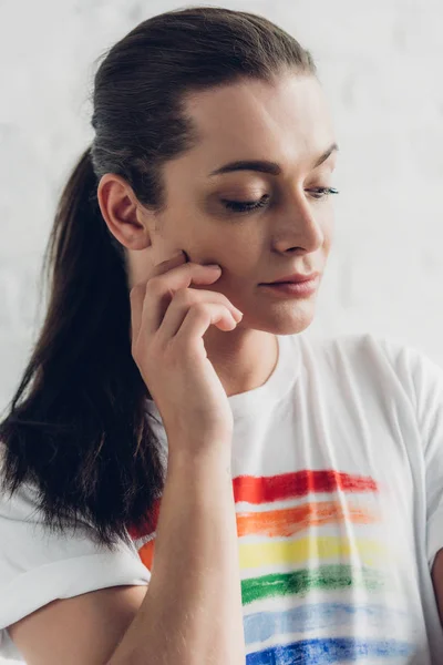 Close-up retrato de jovem mulher transexual em t-shirt branca com bandeira de orgulho na frente da parede de tijolo branco — Fotografia de Stock