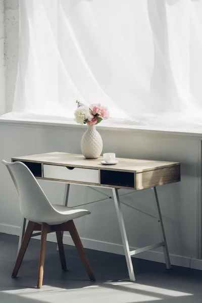 Mesa de trabalho com vaso de flores e xícara de café em casa — Fotografia de Stock