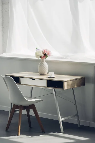 Work desk with vase of flowers and cup of coffee at home — Stock Photo