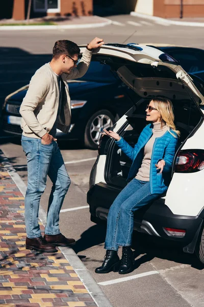 Пара усміхнених туристів розмовляють біля машини на вулиці — стокове фото