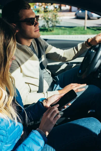 Женщина использует смартфон с пустым экраном во время вождения автомобиля бойфрендом — стоковое фото