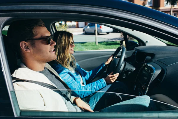 Side view of young woman driving car with boyfriend near by, traveling concept — Stock Photo