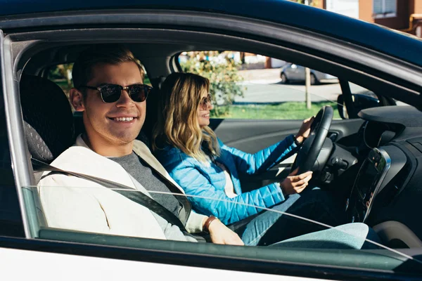 Side view of young woman driving car with smiling boyfriend near by, traveling concept — Stock Photo