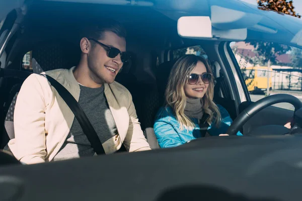 Portrait of smiling young woman driving car with boyfriend near by, traveling concept — Stock Photo