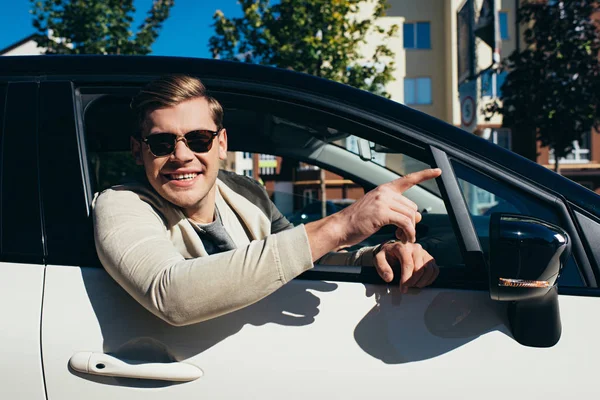 Joven hombre inclinado por la ventana del coche de conducción de automóviles - foto de stock