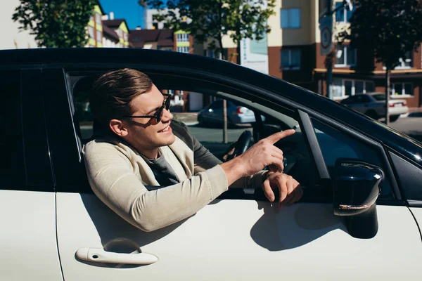 Junger Mann lehnt sich aus Autoscheibe des fahrenden Autos — Stockfoto