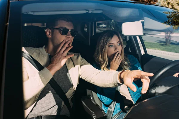 Шокированный мужчина указывая путь к девушке на водительском сиденье в машине — стоковое фото