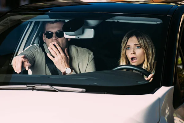 Hombre sorprendido señalando camino a la novia que conduce el coche - foto de stock