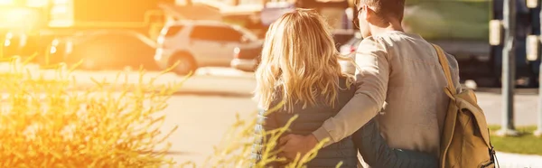 Vista trasera de la pareja abrazándose mientras camina por la calle en la ciudad nueva - foto de stock