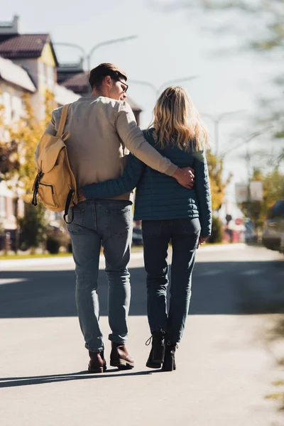 Rückansicht eines Paares, das sich beim Spazierengehen auf der Straße in der neuen Stadt umarmt — Stockfoto