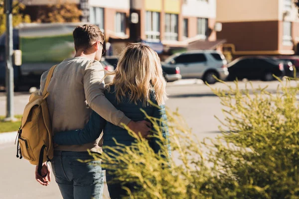 Rückansicht eines Paares, das sich beim Spazierengehen auf der Straße in der neuen Stadt umarmt — Stockfoto