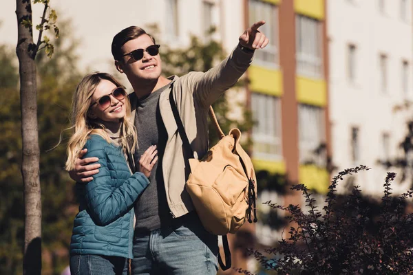 Man showing something to girlfriend while walking together in new city — Stock Photo
