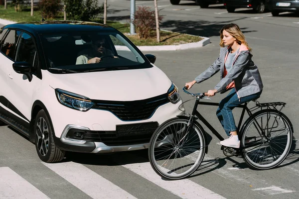 Femme à vélo tout en traversant la route avec chauffeur en voiture — Photo de stock