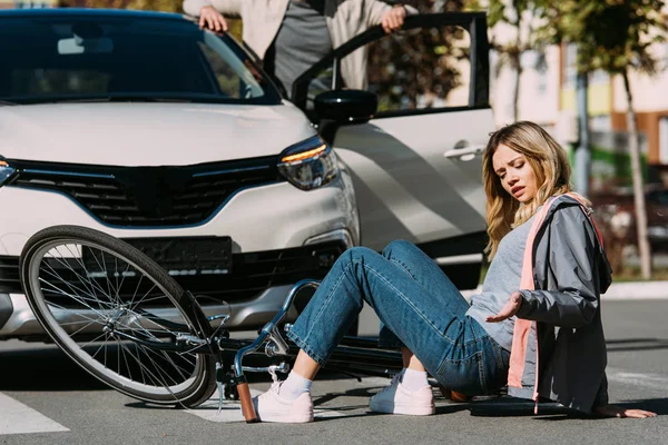 Partial view of young female bicycle rider mowed down by driver in car on road, car accident concept — Stock Photo