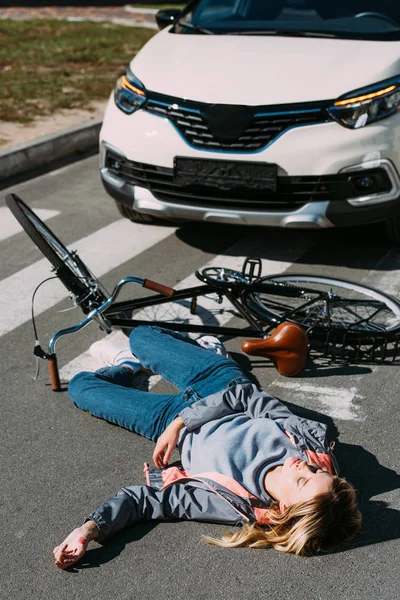 Young woman go mowed down by car while driving bicycle on road, car accident concept — Stock Photo