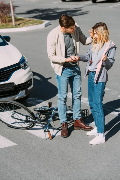 Car driver helping injured young woman after car accident on road — Stock Photo