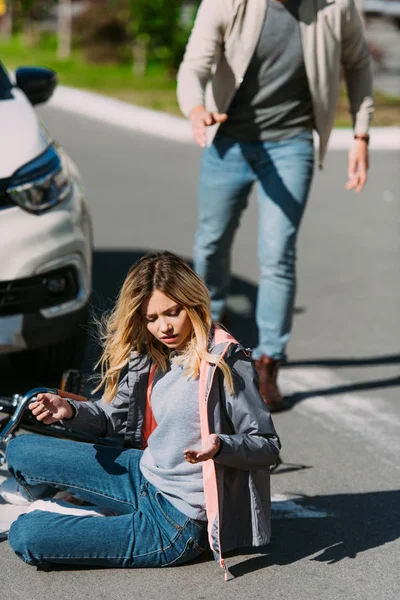 Enfoque selectivo de la mujer lesionada en la carretera después de un accidente de coche con el conductor detrás - foto de stock