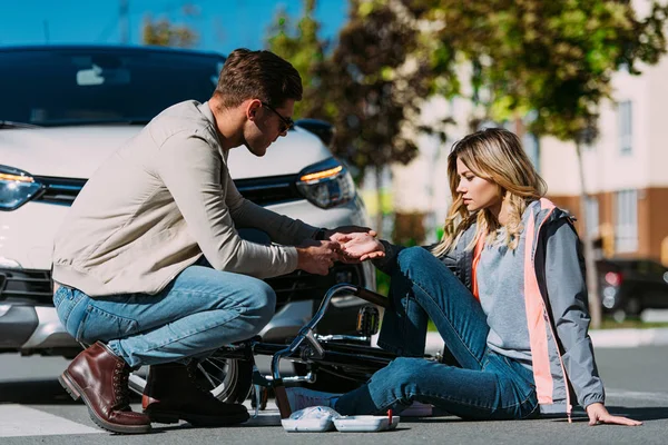 Man getting first air to injured woman after car accident on road — Stock Photo