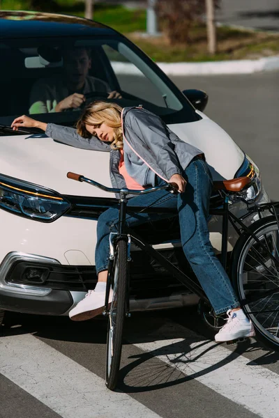 Молода жінка ковзала вниз на машині під час їзди на велосипеді на дорозі, концепція автокатастрофи — стокове фото