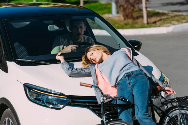 Young woman go mowed down by car while driving bicycle on road, car accident concept — Stock Photo