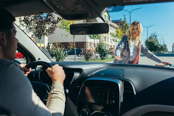 Jeune femme querelle avec le conducteur de voiture tout en traversant la route — Photo de stock