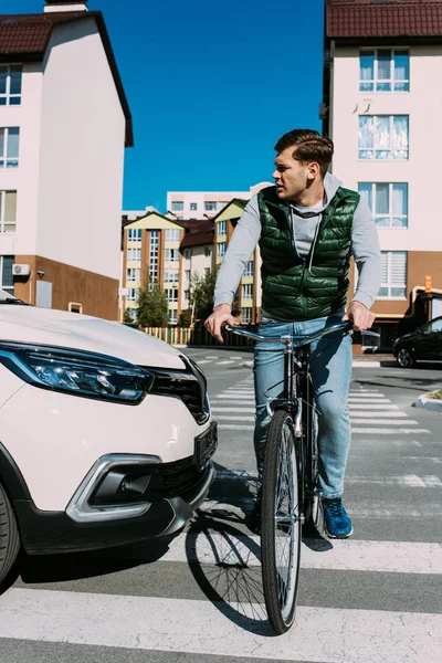 Homme sur vélo traversant la route tandis que le conducteur en voiture attend — Photo de stock