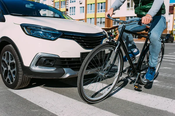 Partial view of man on bicycle crossing road while driver in car waiting — Stock Photo