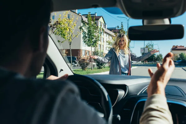 Mujer joven peleando con el conductor del coche mientras cruza la carretera - foto de stock