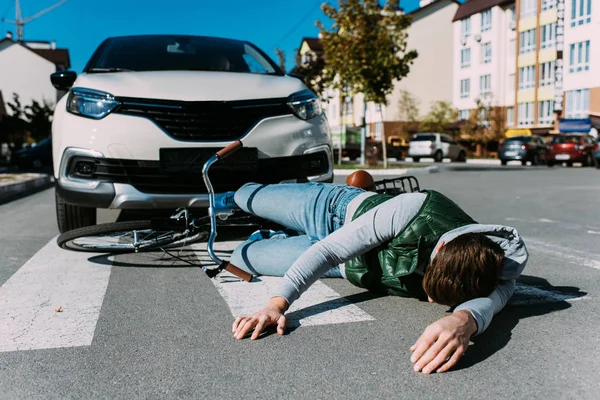 Ciclista masculino golpeado por el coche en la carretera, concepto de accidente de coche - foto de stock