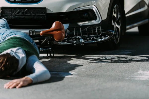 Partial view of male bicycle rider hit by car on road, car accident concept — Stock Photo