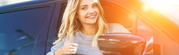 Retrato de loira sorrindo mulher mostrando polegar para cima durante a condução de carro — Fotografia de Stock