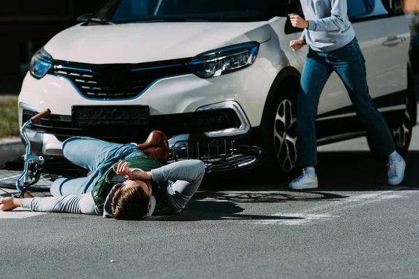Cropped shot of woman running to injured cyclist at traffic accident — Stock Photo