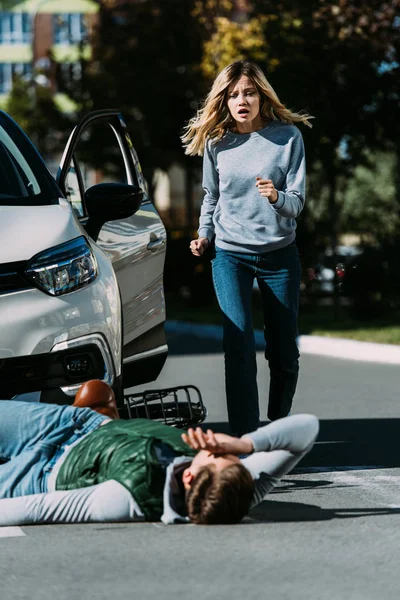 Femme choquée courant à cycliste blessé lors d'une collision de la circulation — Photo de stock