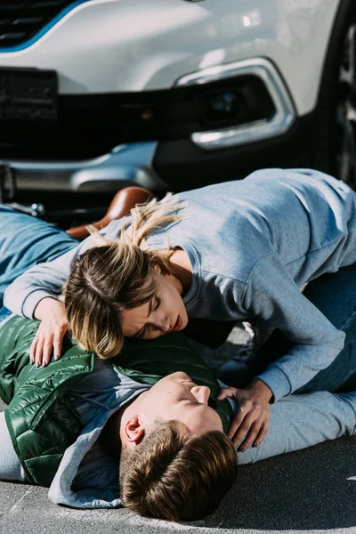 Mujer joven escuchando latidos del corazón del ciclista lesionado después de un accidente de coche - foto de stock