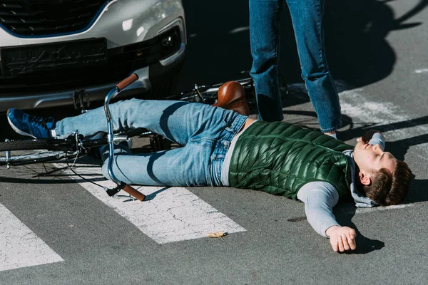 Cropped shot of woman standing near injured cyclist after car accident — Stock Photo