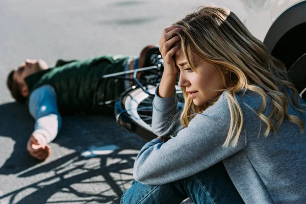 Mujer asustada llorando cerca de coche después de colisión de tráfico con ciclista - foto de stock